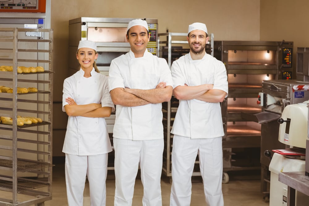 Team of bakers smiling at camera in a commercial kitchen